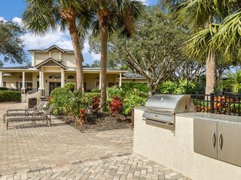 A patio with a grill and a house in the background